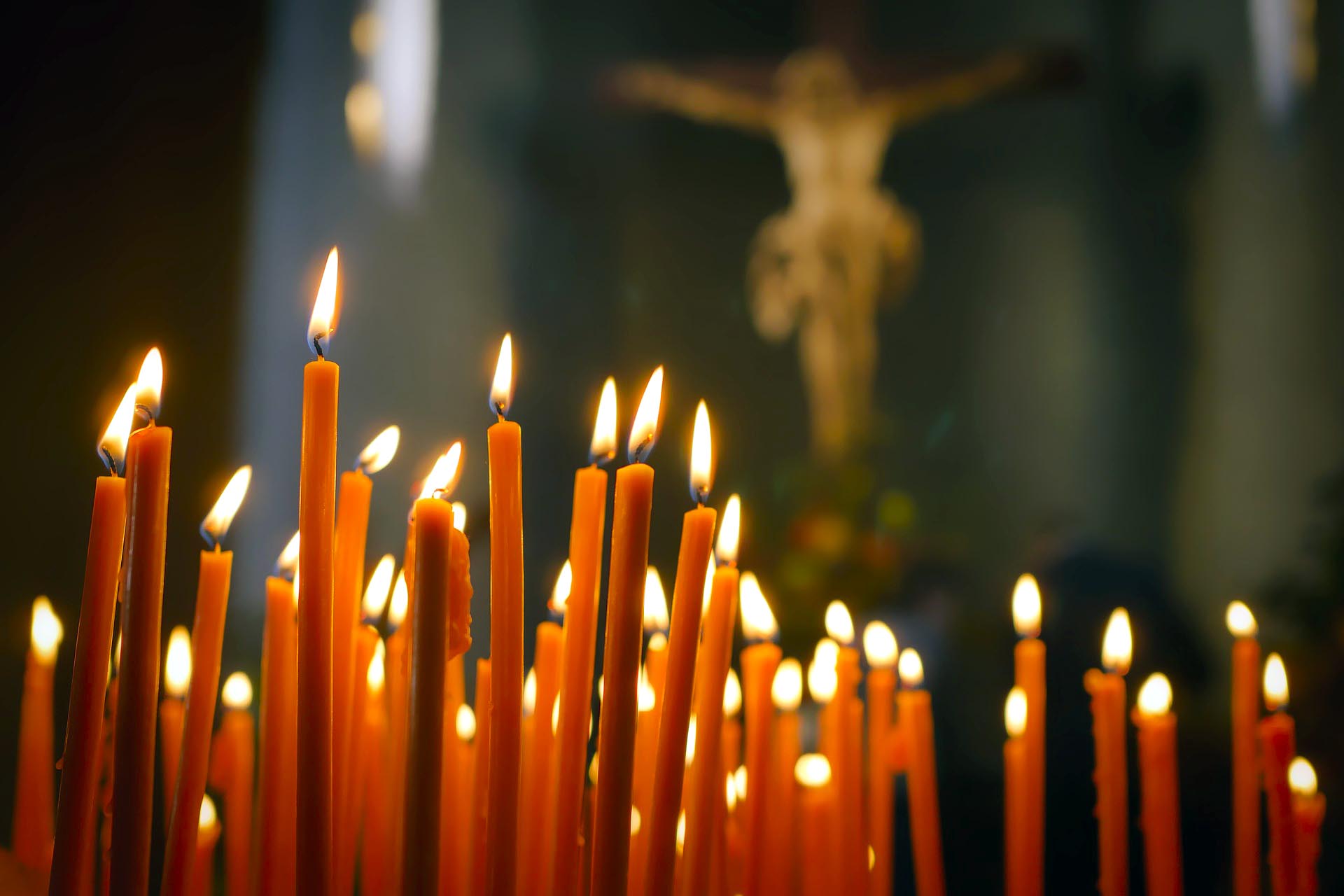 Palavia punaisia kynttilöitä, taustalla alttaritaulu, jossa Jeesus ristillä.