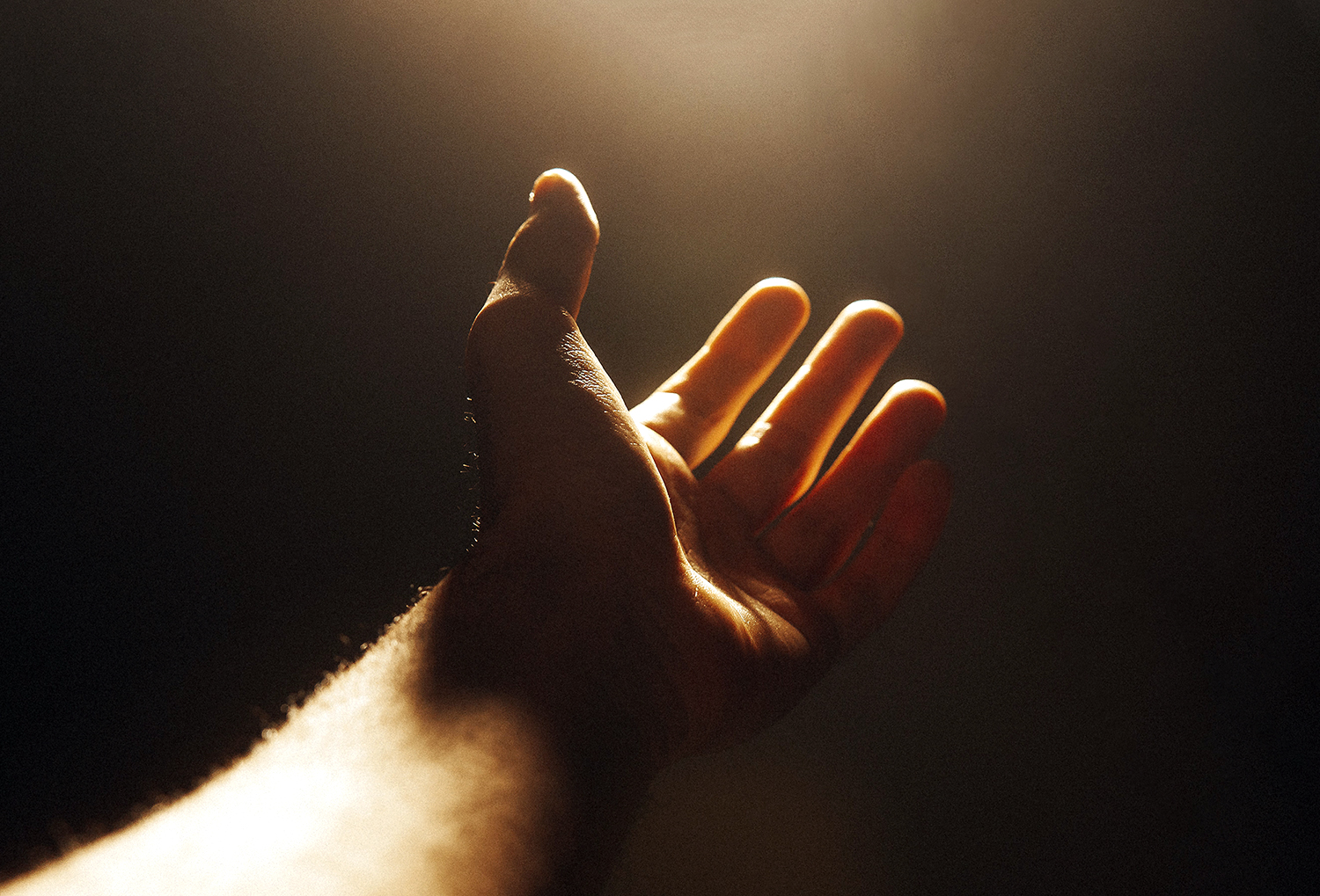 Käsi ojentuu kohti valoa.