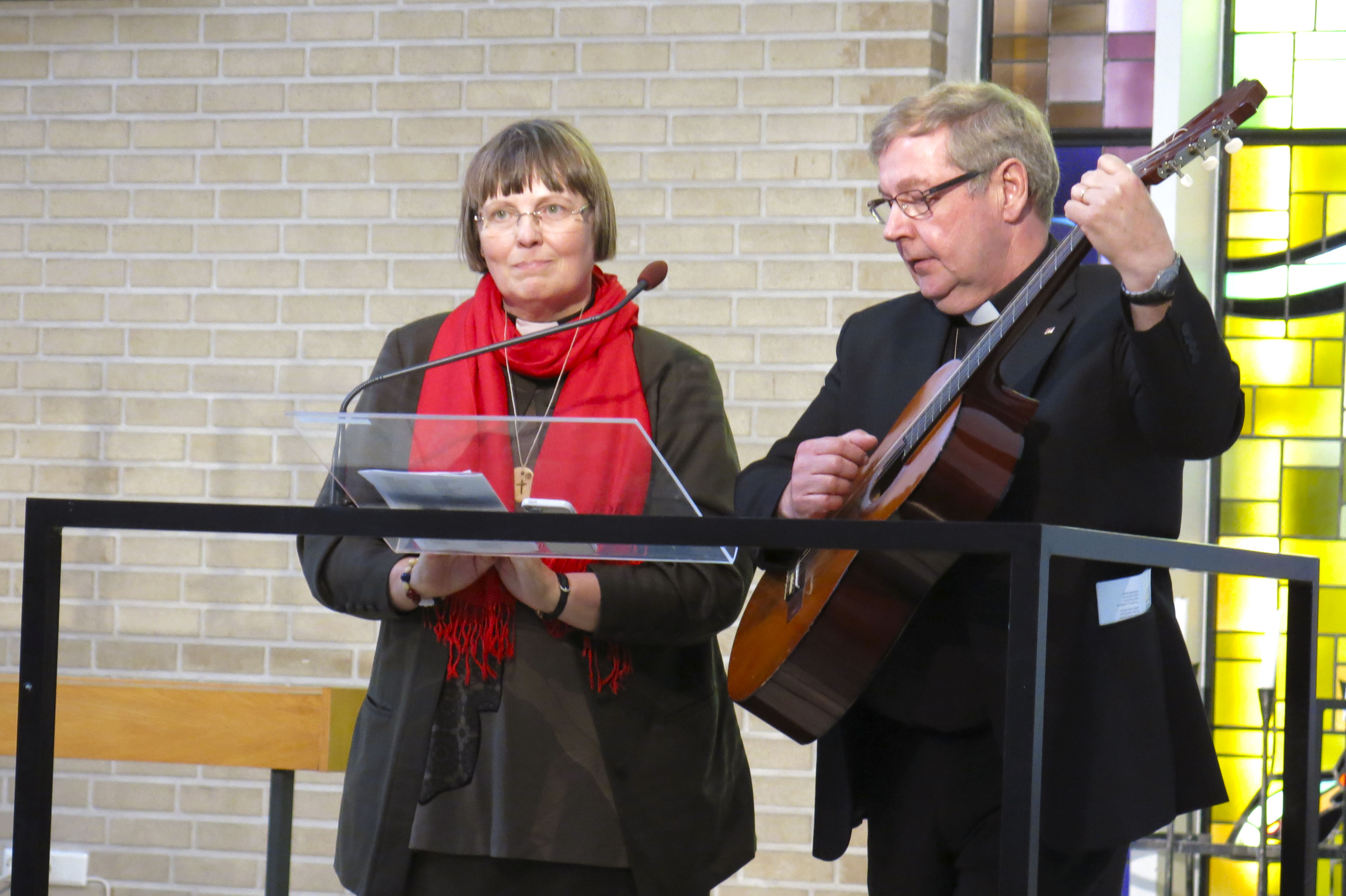 Pappi soittaa kitaraa eläkkeelle jäävälle kehitysvammaistyön papille Leena Luokkamäelle.